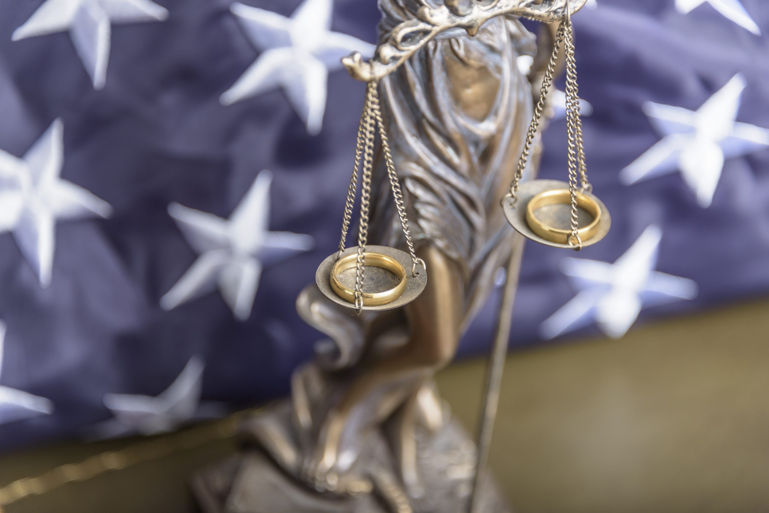 The statue of justice Themis or Iustitia, the goddess of justice blindfolded against a flag of the United States of America, as a legal concept.